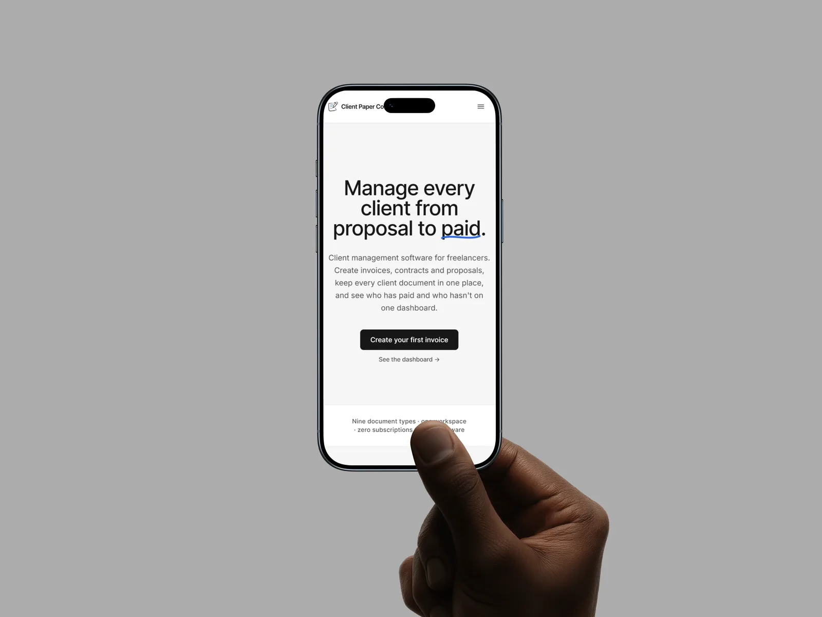 A hand holding a phone showing the Client Paper Co. freelance invoicing app open on its home screen