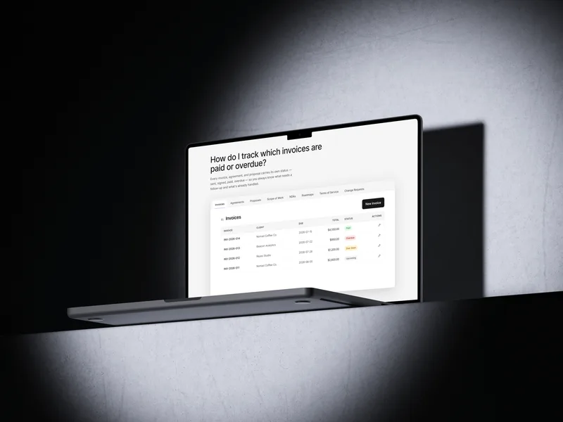 A MacBook on a concrete shelf showing the Client Paper Co. invoice list with paid, overdue, due-soon, and upcoming statuses